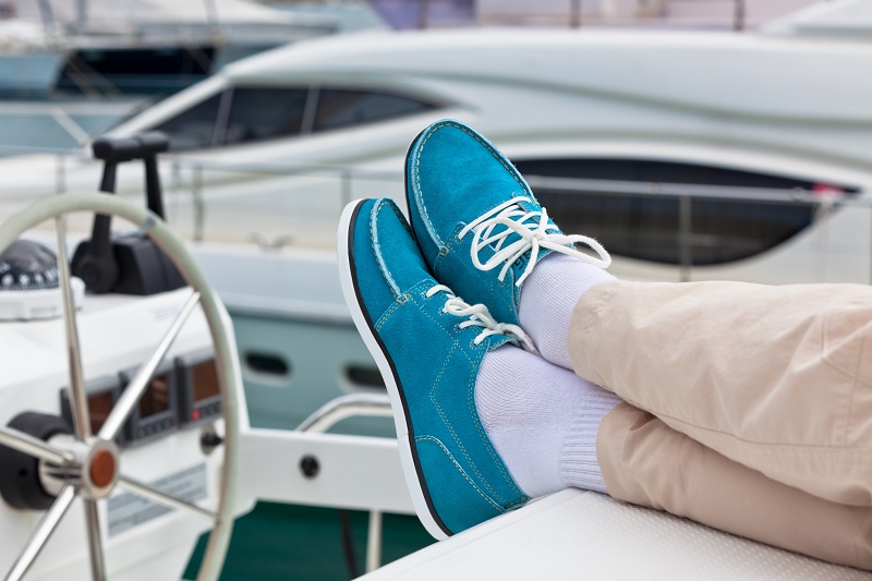 Casual Boat Shoes: Effortlessly Stylish A pair of human legs in pants and bright blue topsiders on yacht deck background. Yachting