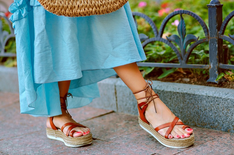 Platform Sandals: Height with Comfort Close up fashion details of woman feet, elegant gladiator sandals, blue feminine dress, perfect for summer vacation.